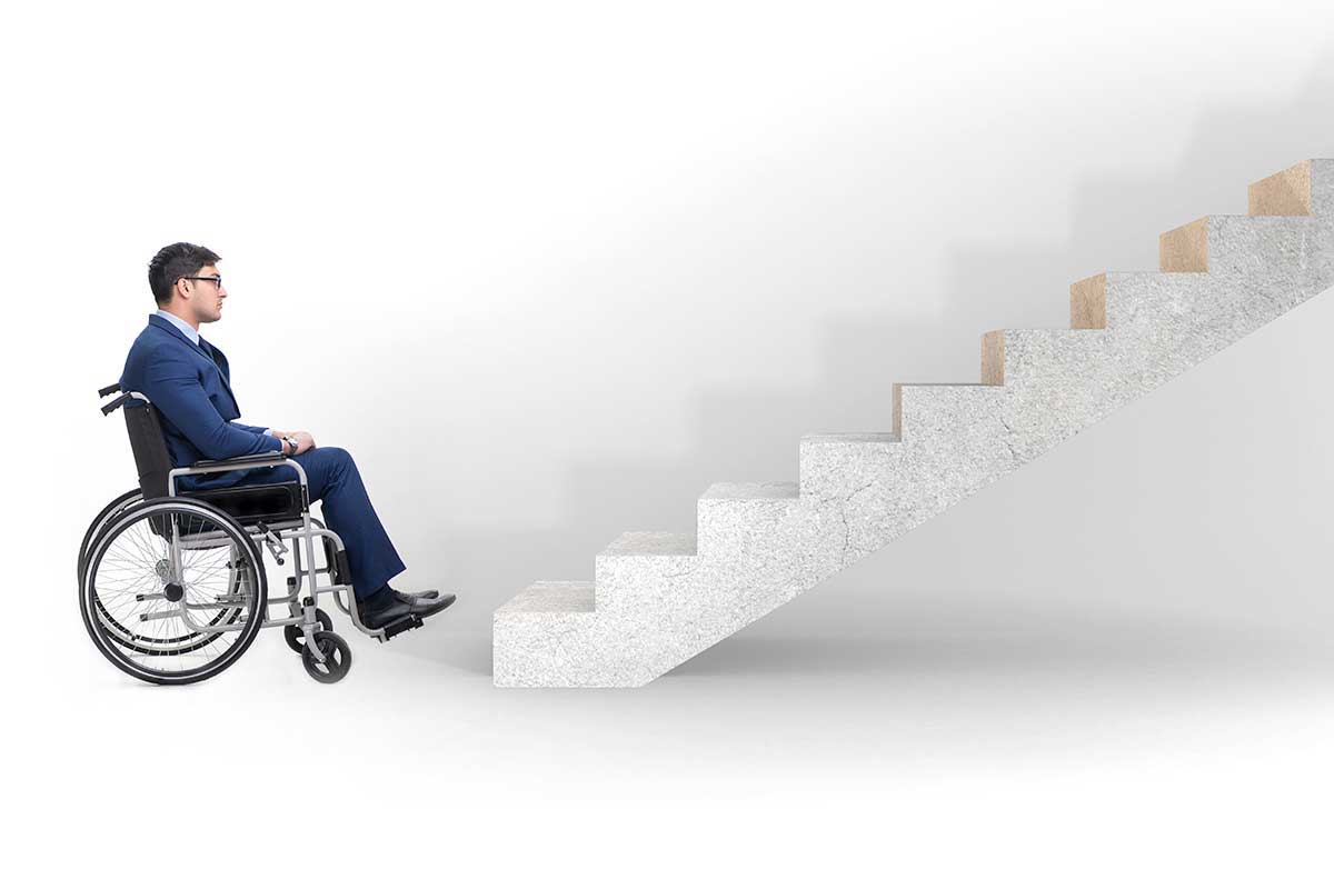 A disabled person in a wheelchair in front of a stairs